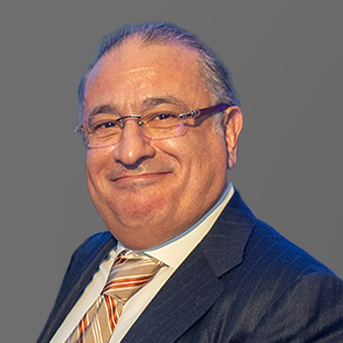 Male wearing glasses and suit in front of gray background.