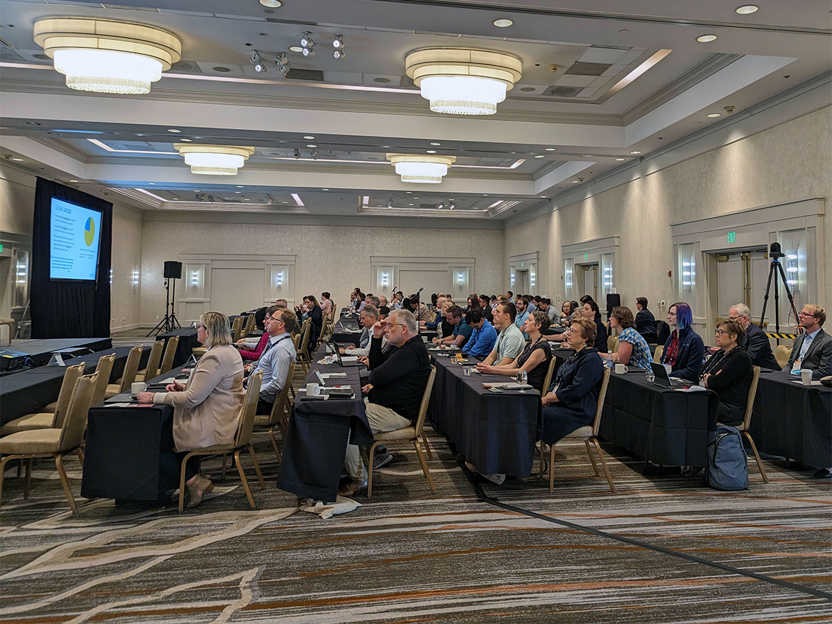 Biopharmaceutical attendees sitting at tables in a large ballroom listening to a scientific presentation at Bioassays 2023.