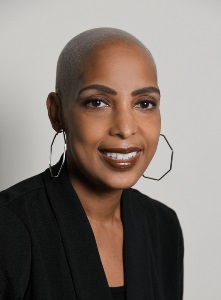 Carolyn Slade in a black shirt and hoop earrings.