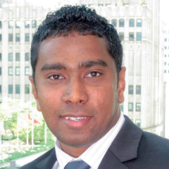 Image of male in business suit with tall buildings in the background.