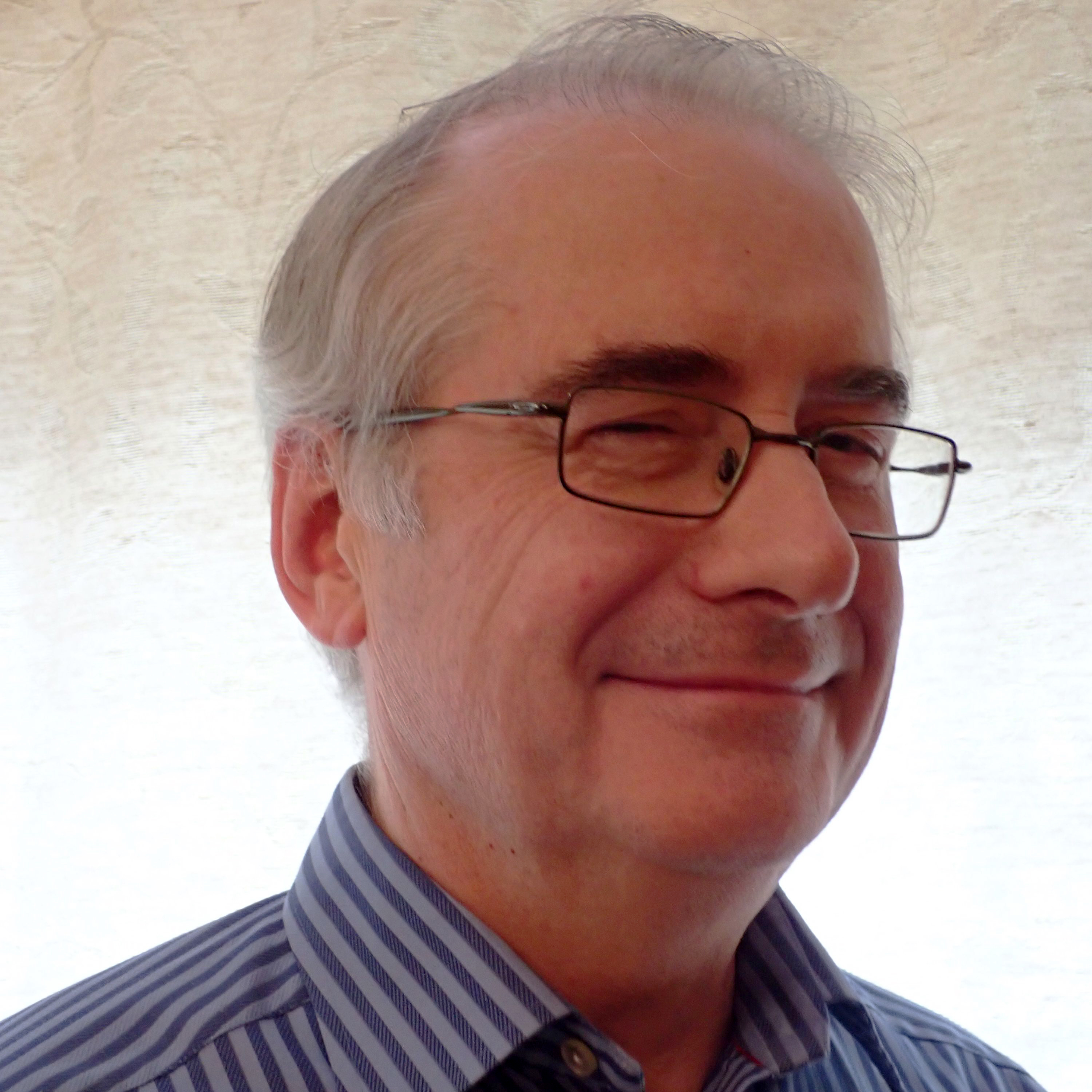 Image of man with gray hair and glasses in collared shirt.