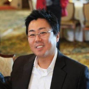 Image of one male sitting indoors in banquet hall