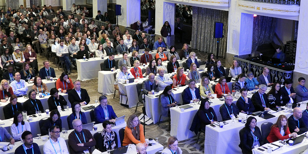 Ballroom of conference attendees watching a speaker presentation